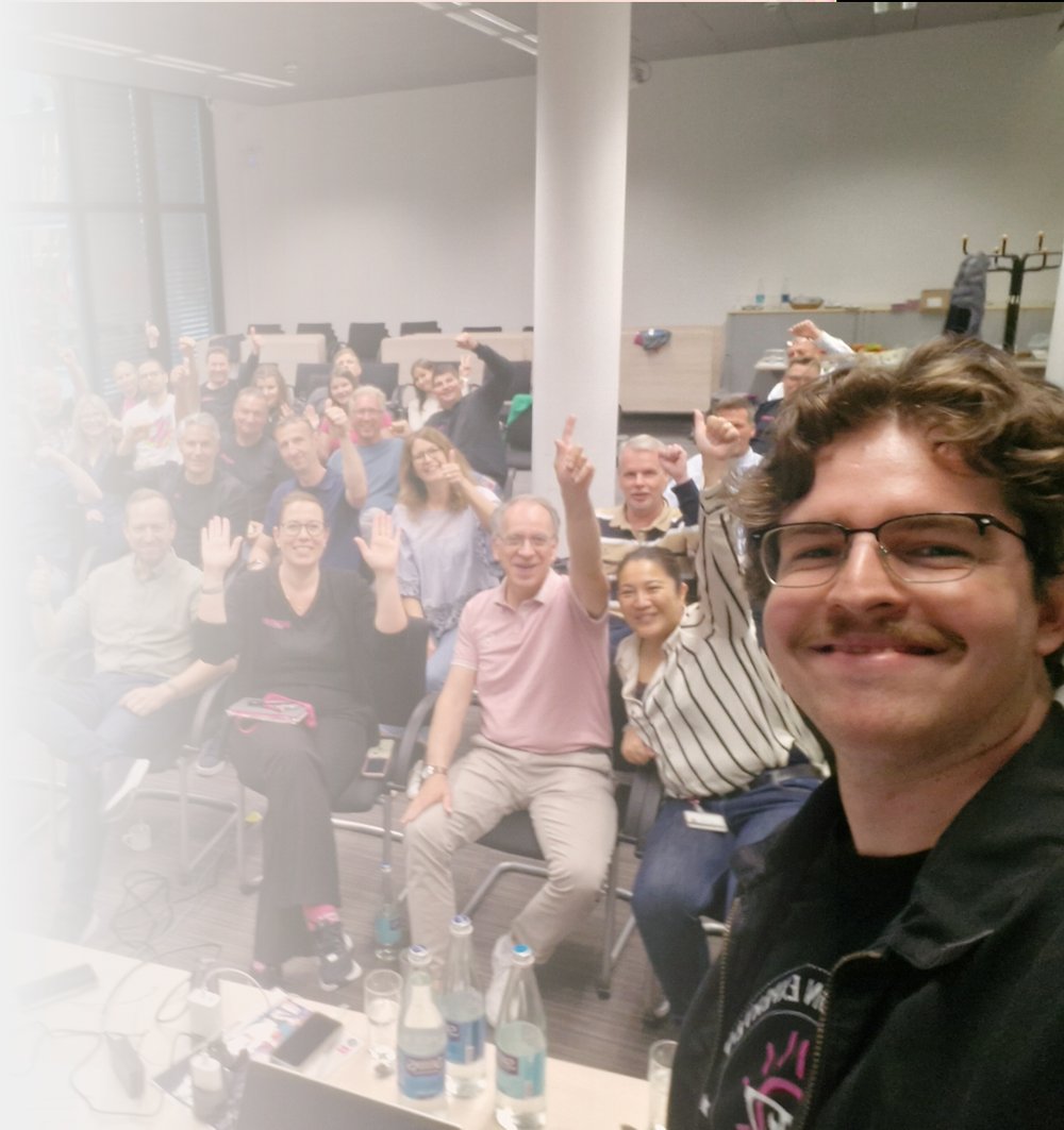 Selfie vor vollem Schulungsraum, Teilnehmende heben die Daumen
