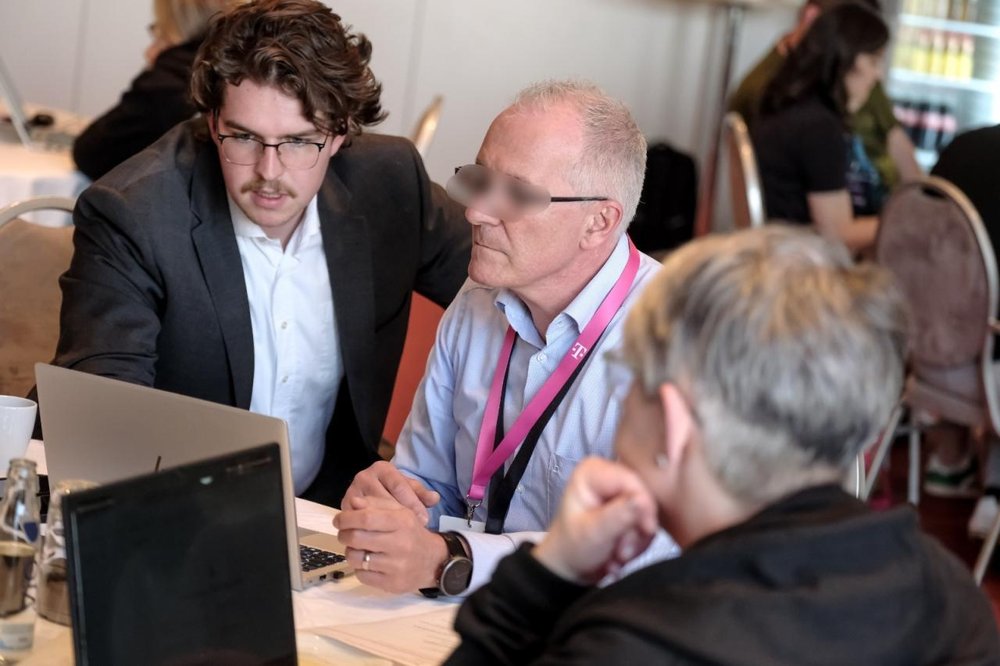 Matteo Möller im Gespräch mit Teilnehmenden an einem Tisch mit Laptop