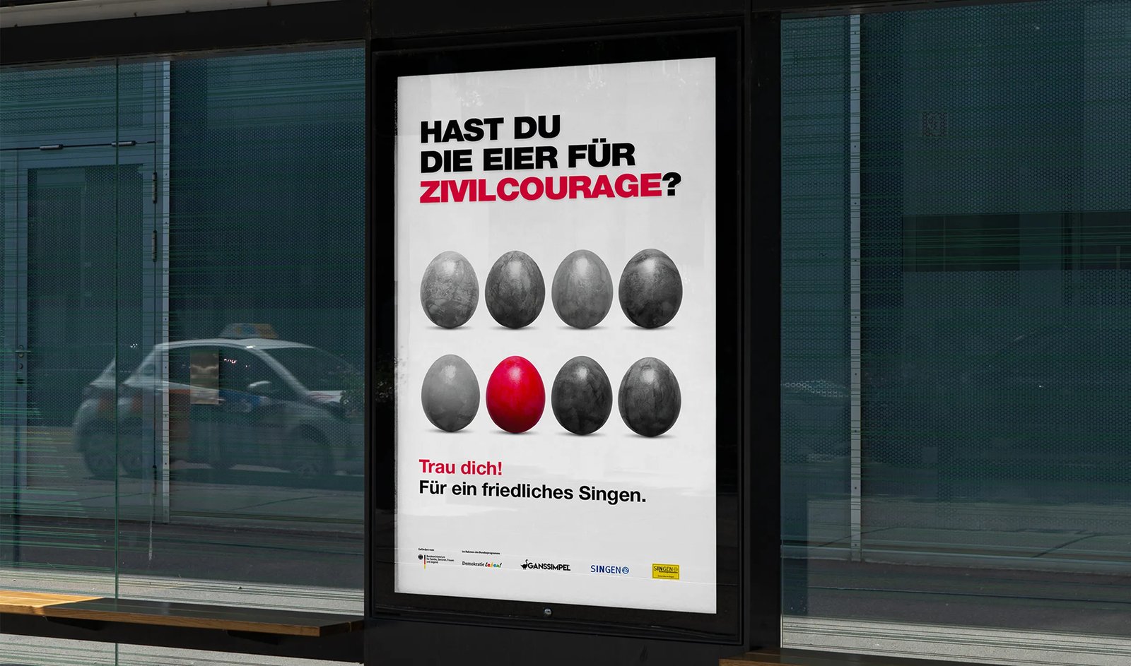 Bushaltestellen-Plakat mit der Aufschrift ‚HAST DU DIE EIER FÜR ZIVILCOURAGE?' und einem Raster aus acht grauen Eiern, eines davon rot